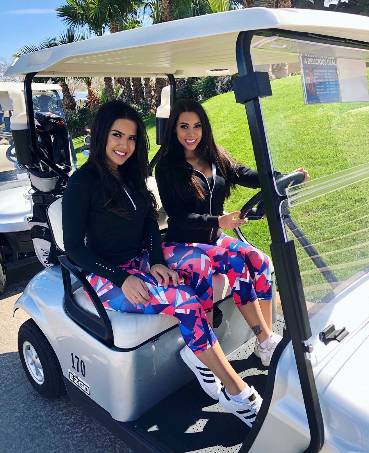 Model caddy hostesses drive a golf cart on Angel Park Golf Club course in Las Vegas.