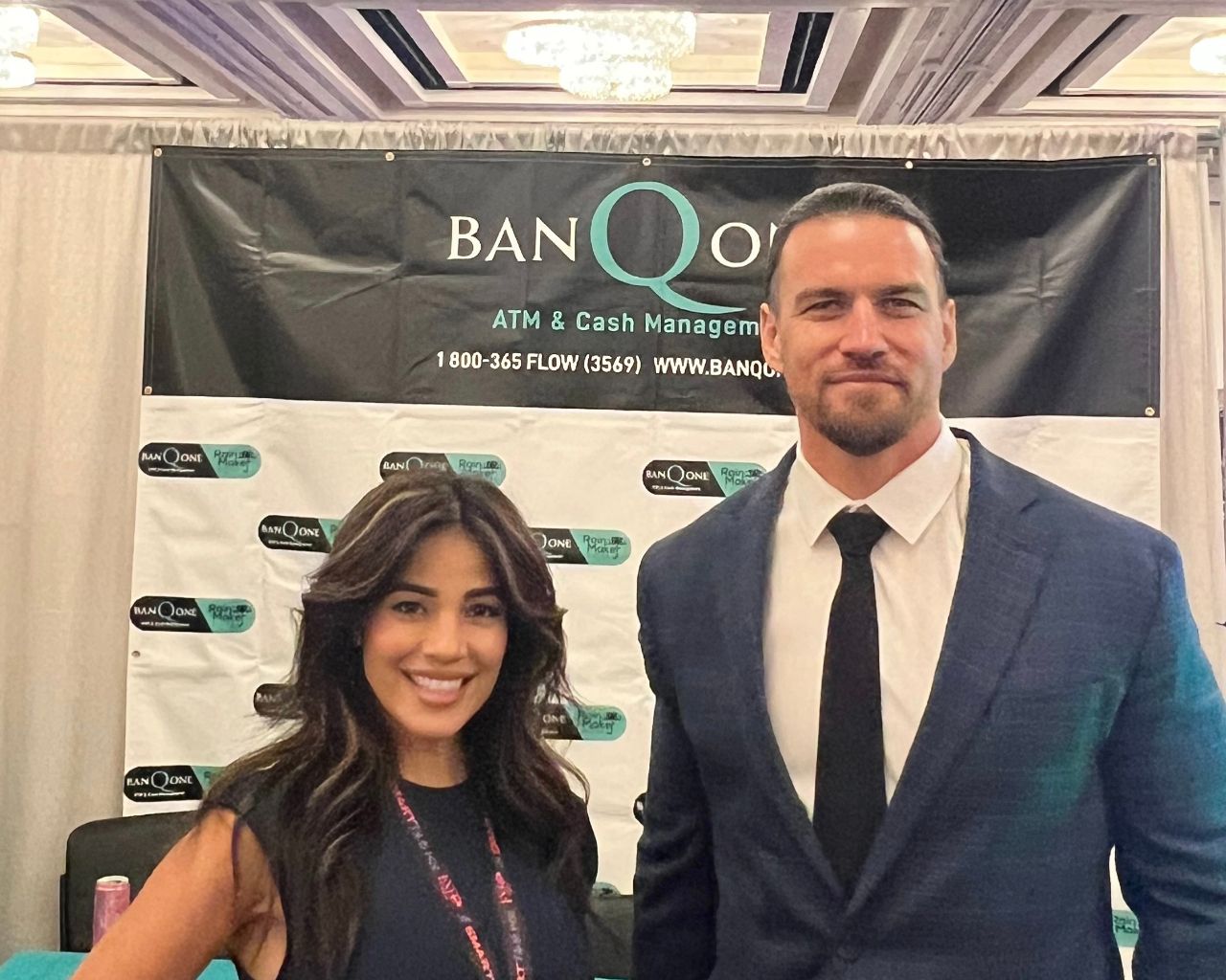 Woman and a man in a suit stand in front of a banner for BanQ ATM & Event Management.