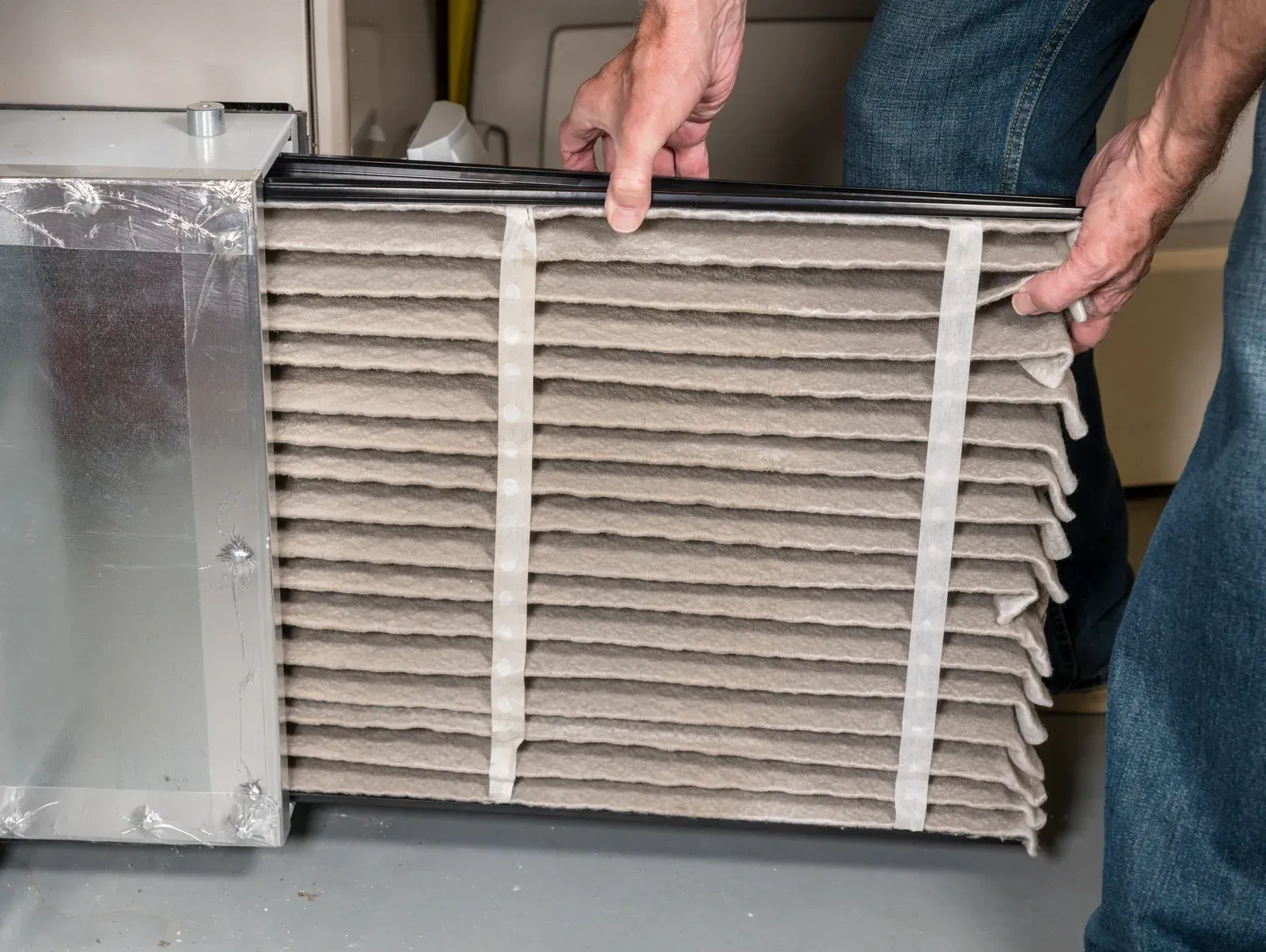 Person removing a dirty furnace filter from its housing.