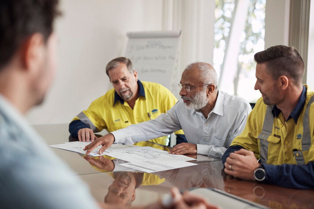 A group of men are sitting around a table having a meeting.