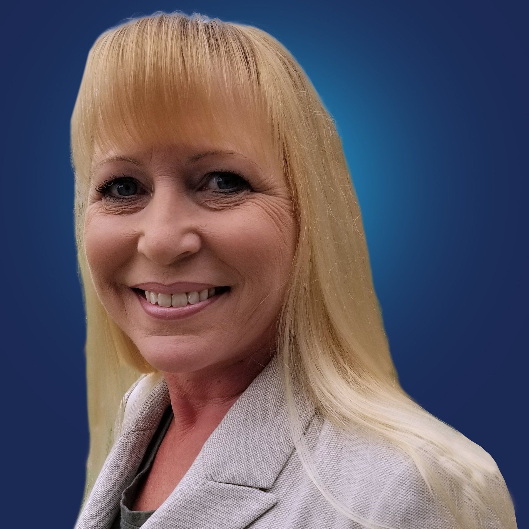 A woman with blonde hair is smiling and wearing a white jacket