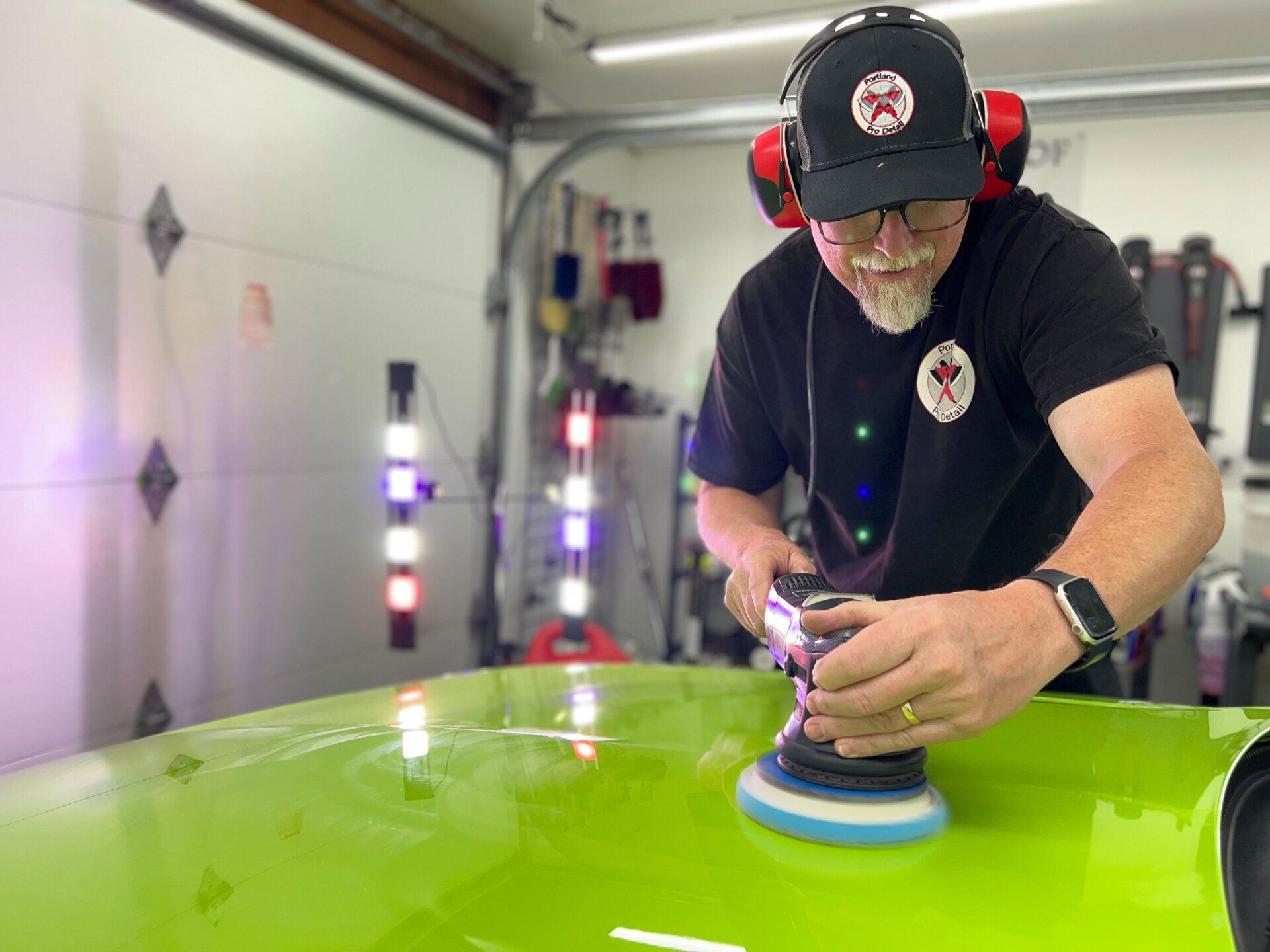 a man is polishing a green car in a garage .