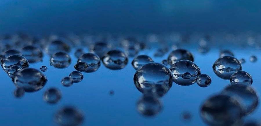 a close up of water bubbles on a blue surface .
