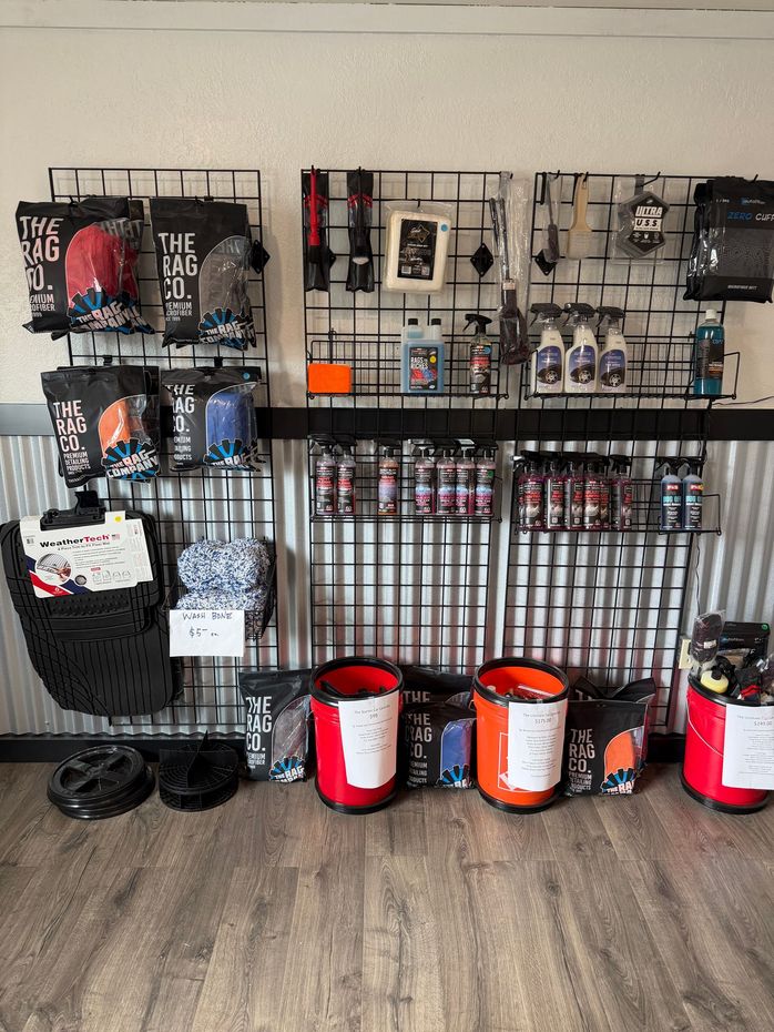 Retail display of fishing and outdoor gear on wall racks, with red and black buckets on the floor