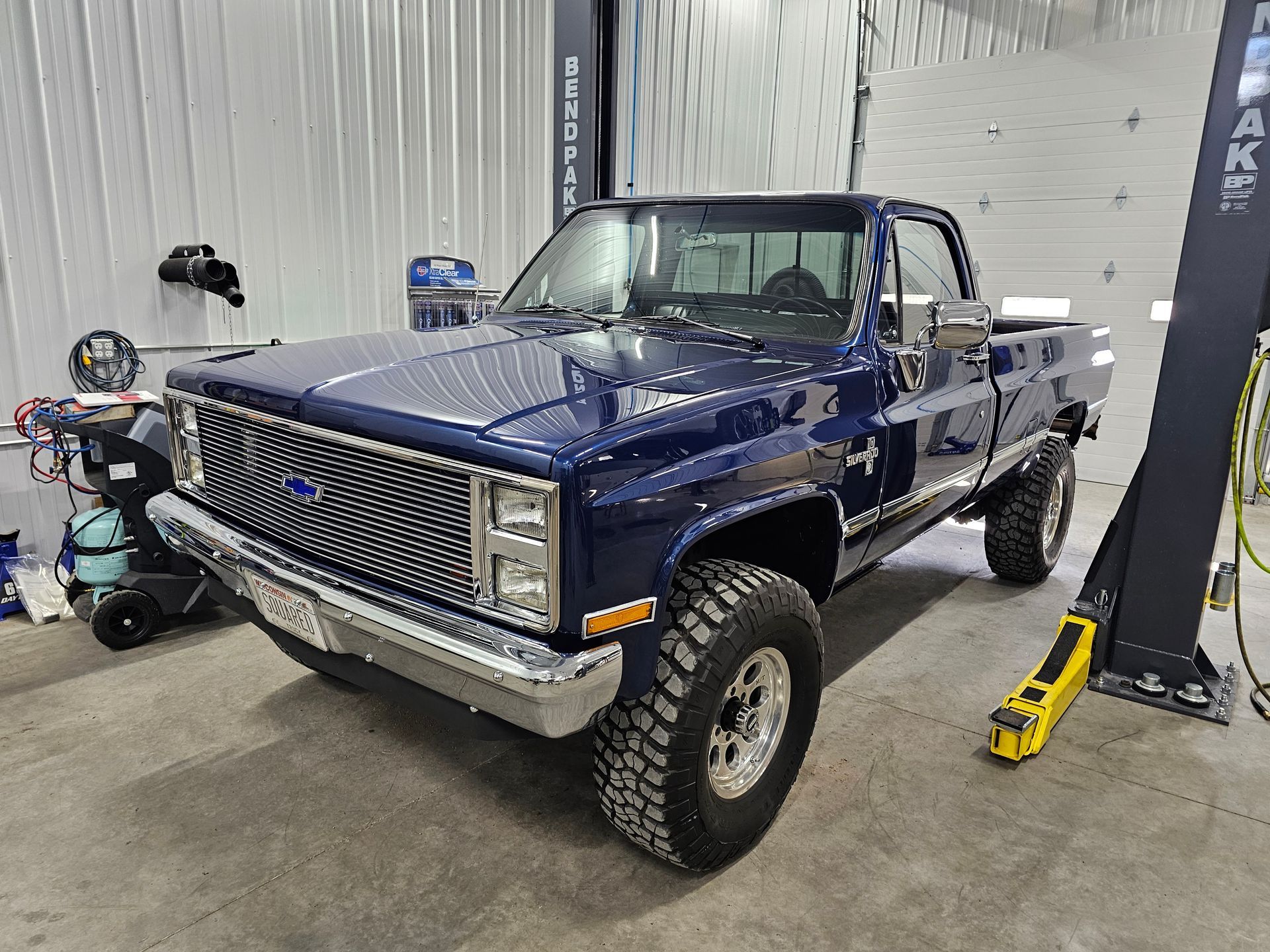 A blue truck is parked on a lift in a garage.