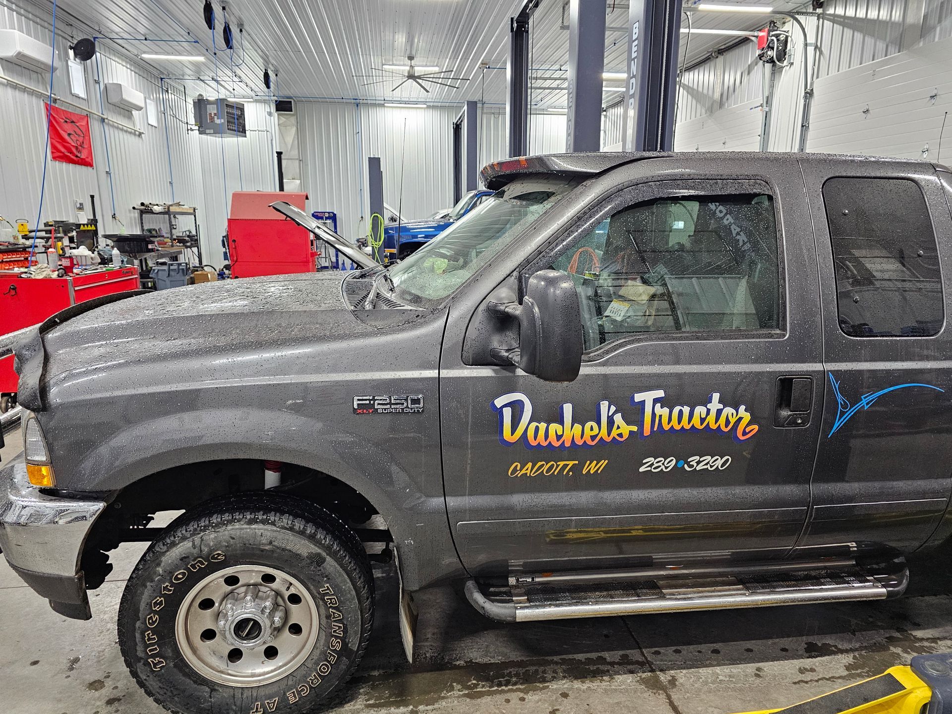 A black truck with bachelor tractors written on the side is parked in a garage.
