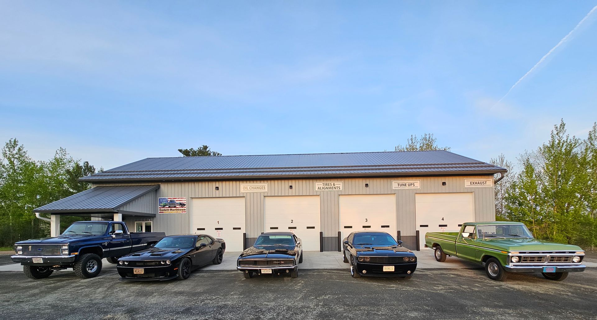 A row of cars are parked in front of a garage.