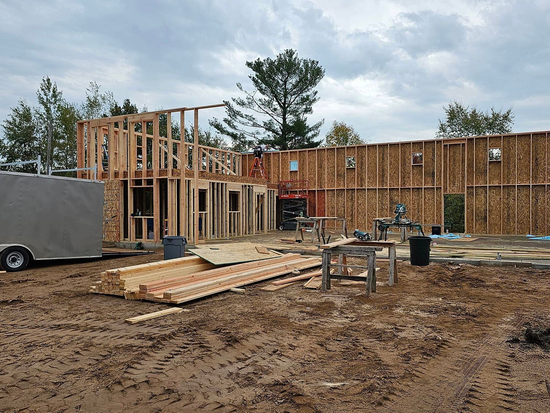 a house is being built in a dirt field with a trailer in the background .