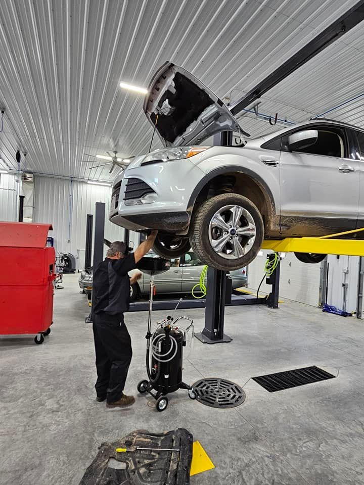 a man is working on a car on a lift in a garage .