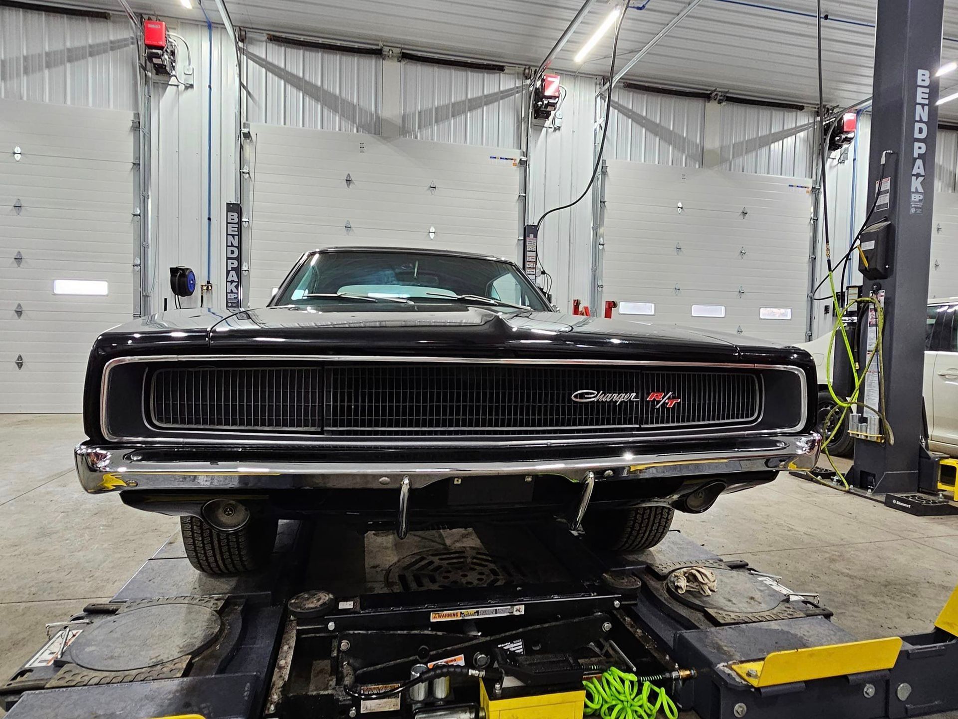 a black dodge charger is parked on a lift in a garage .