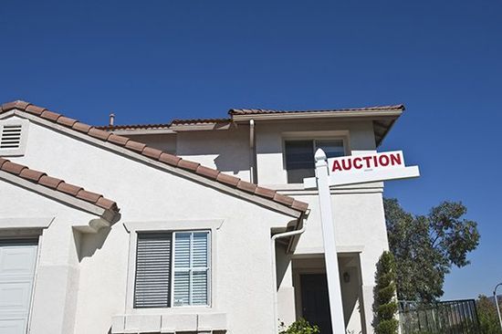 House with auction Sign against blue sky