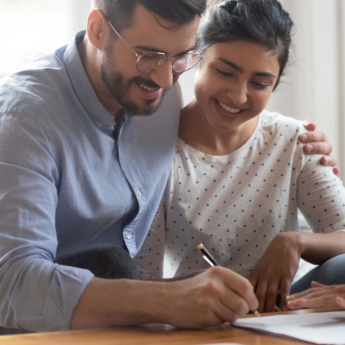 A man and a woman are sitting at a table writing on a piece of paper.