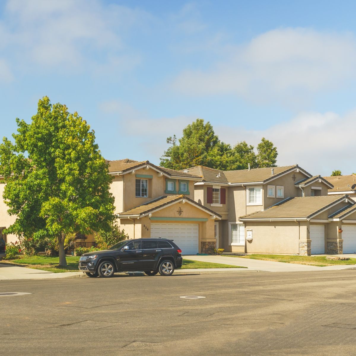 A black suv is parked in front of a row of houses