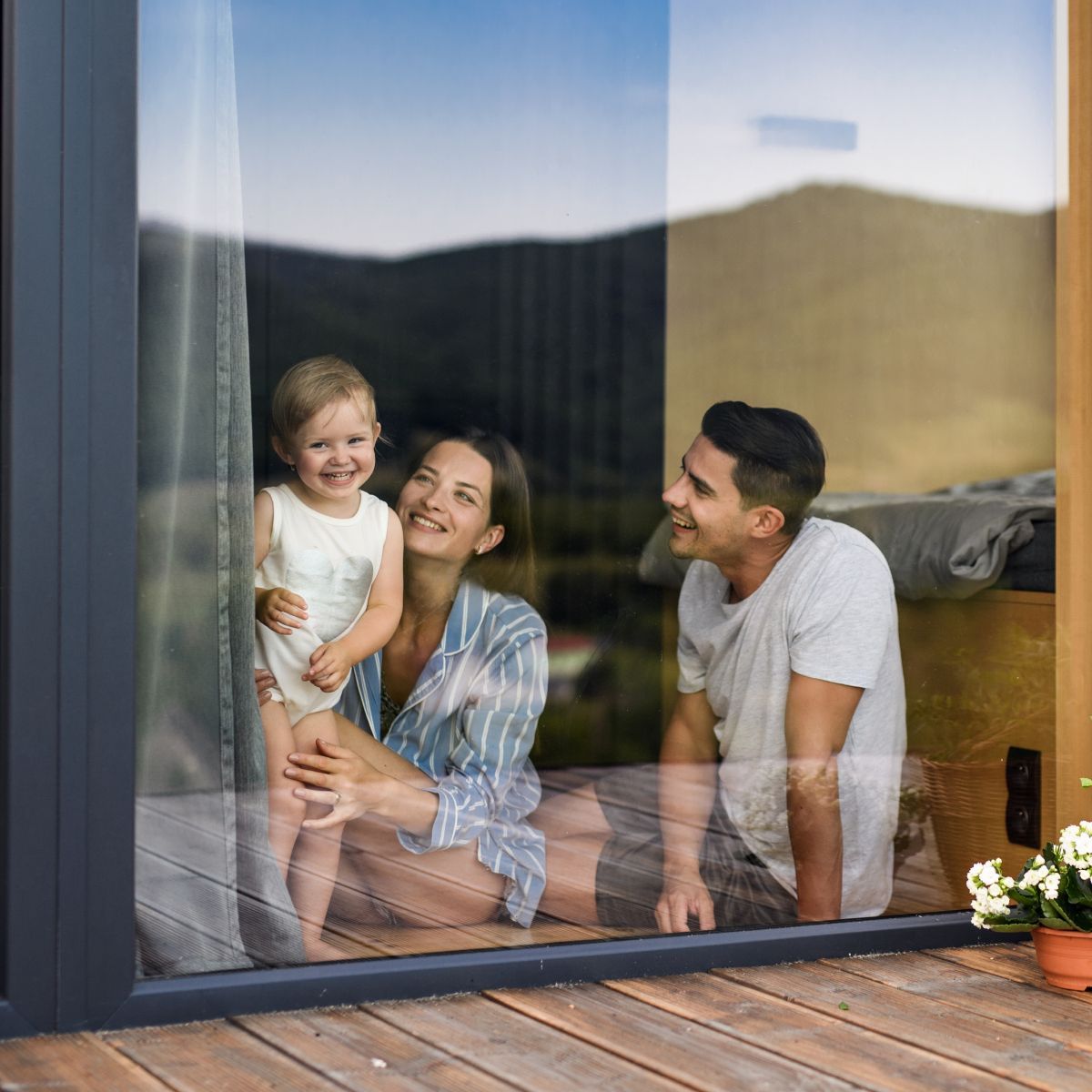 A man , woman and child are looking out of a window.