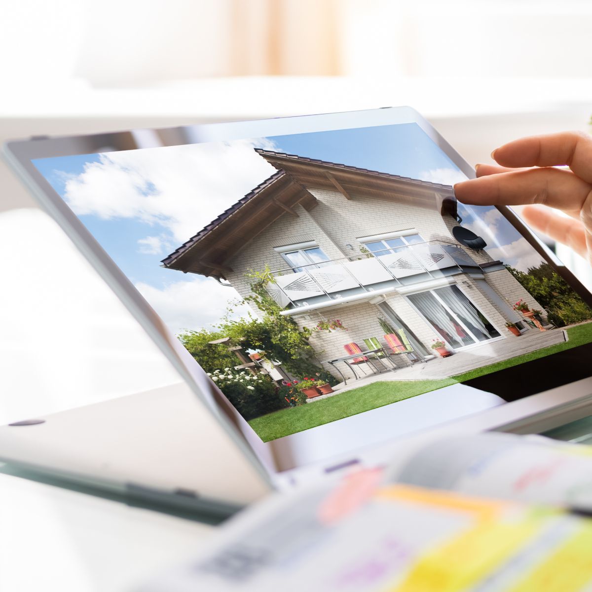 A person is looking at a picture of a house on a tablet