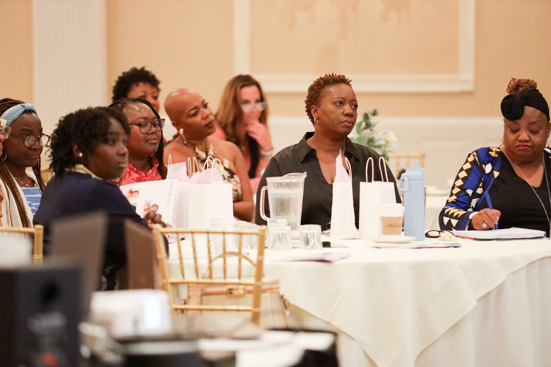 People seated at a table in a well-lit room, possibly a conference or meeting.