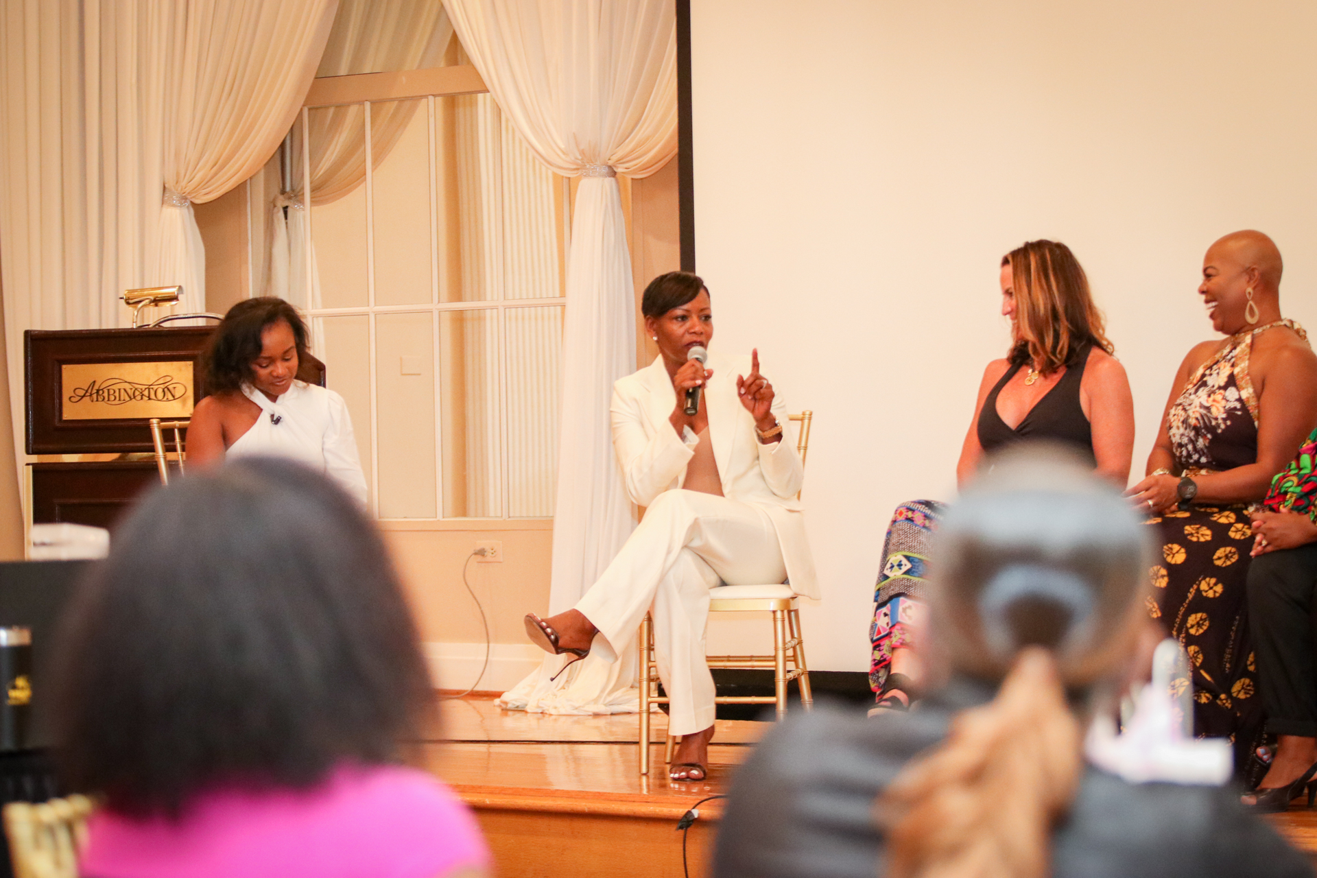 A panel of women on stage at an event, speaking to an audience.
