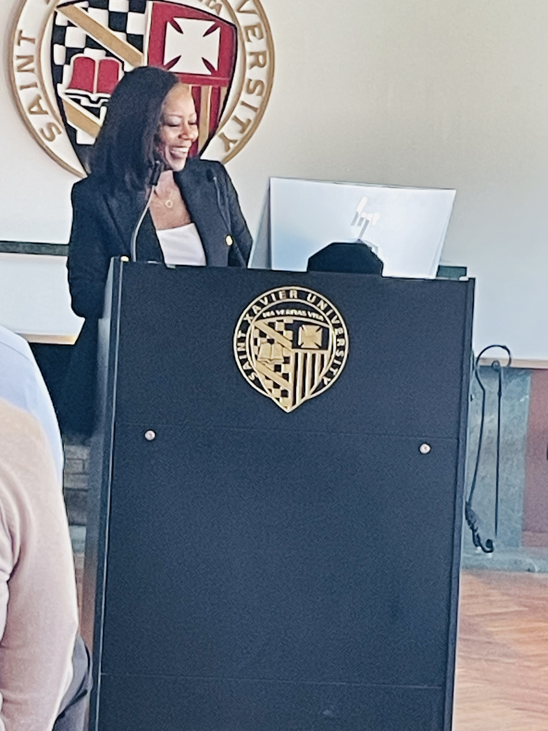 Image of Isabel speaking at a black podium at Xavier University