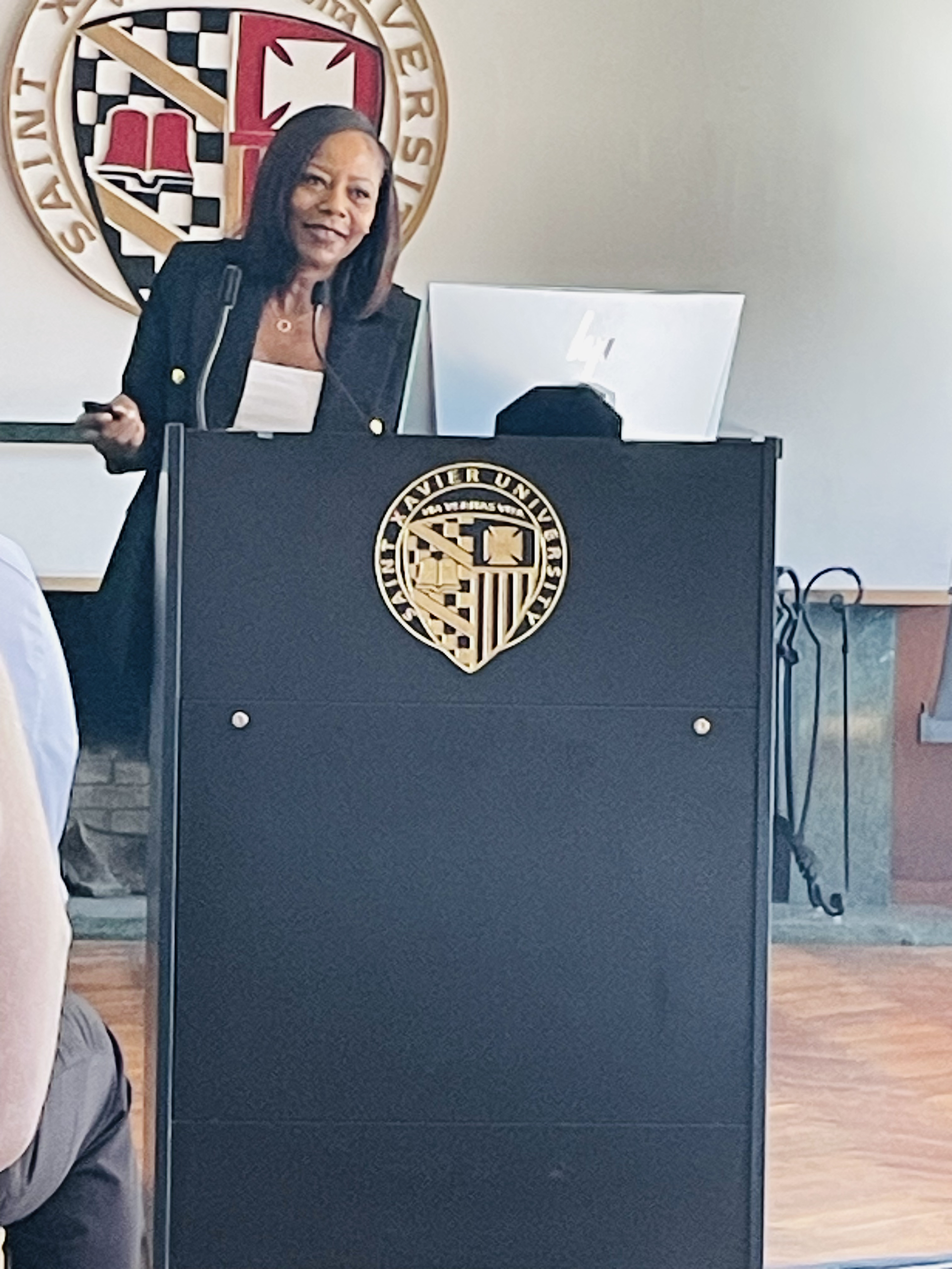 Image of Isabel speaking at a black podium at Xavier University