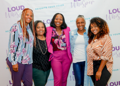 Five women standing in front of a backdrop with