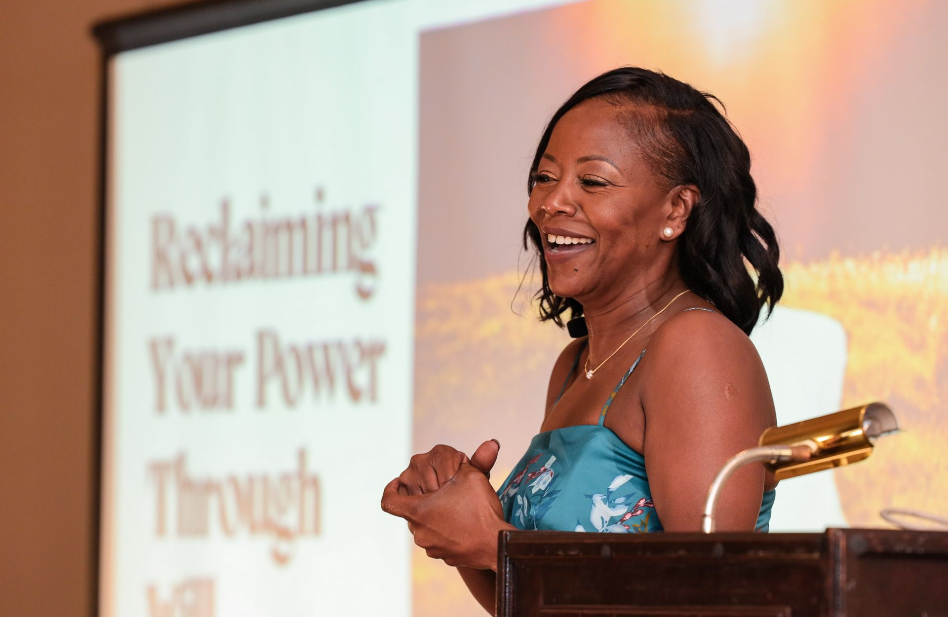 Woman speaking at a presentation, smiling. Text on screen: 