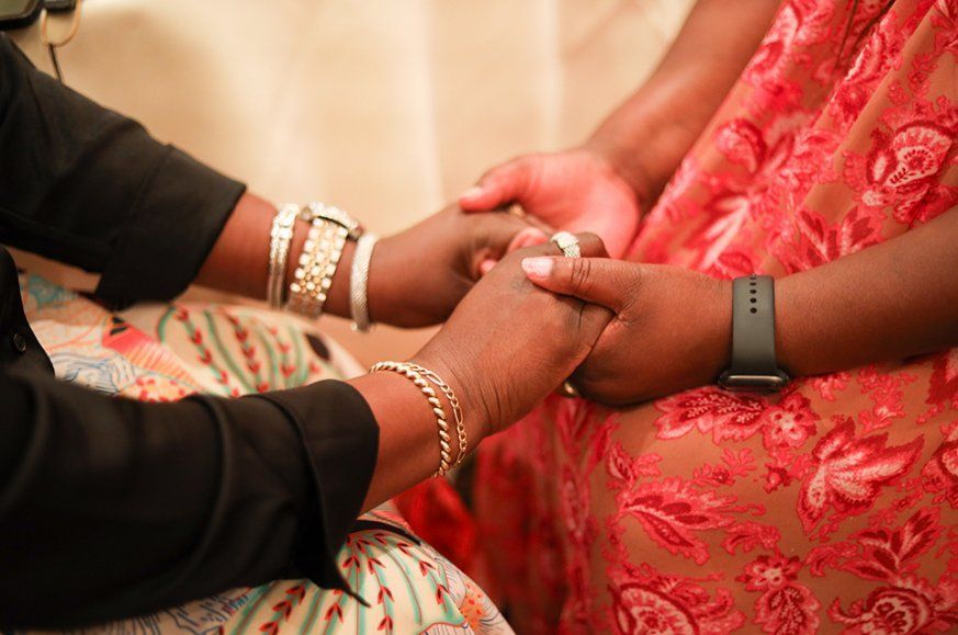 Two people holding hands, one wearing jewelry, the other wearing a smartwatch.