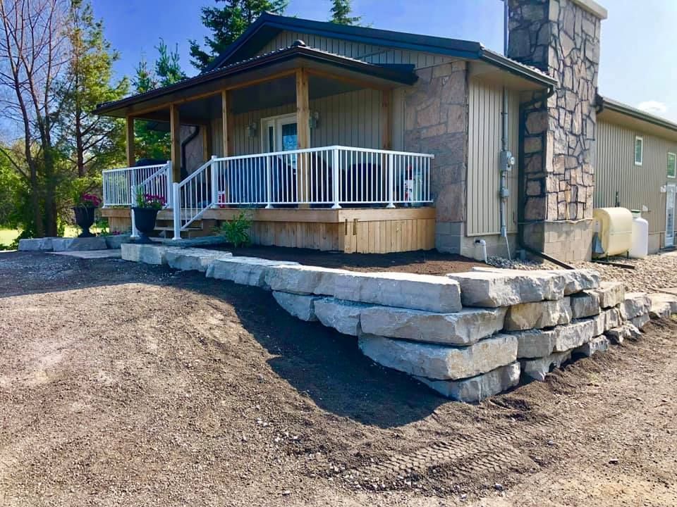 A house with a porch and a stone wall in front of it.