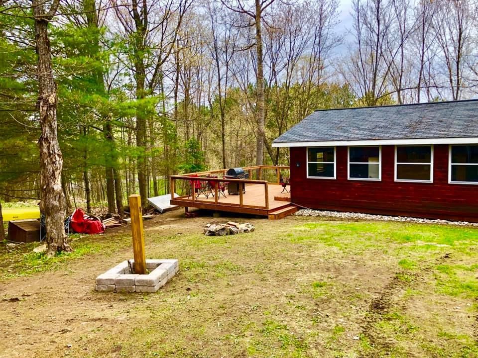 A small red house with a deck and a fire pit in the backyard.