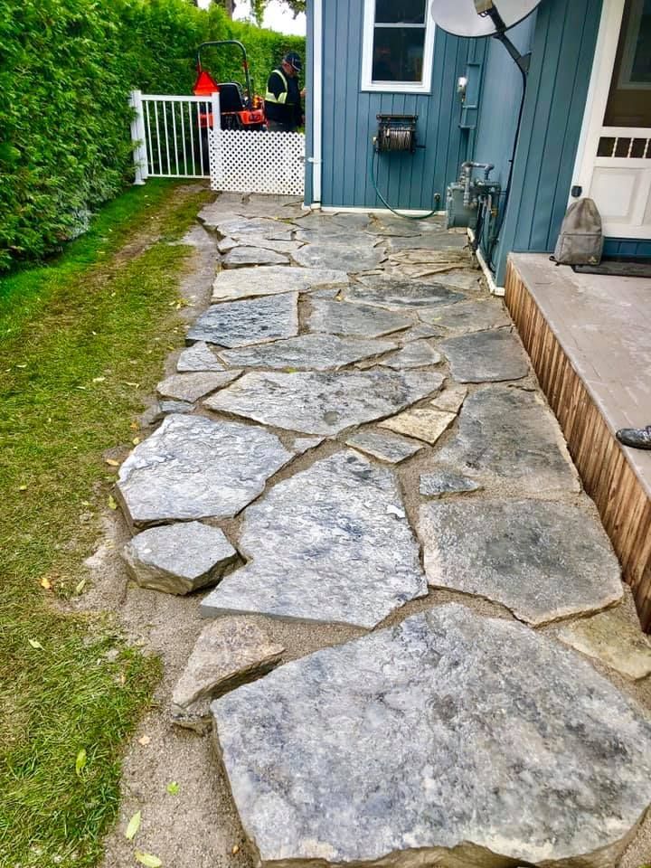 A stone walkway leading to a blue house.