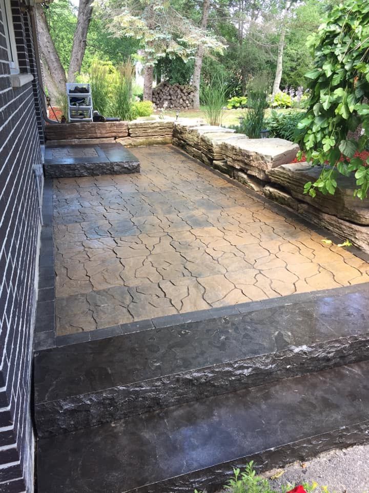 A patio with a brick wall and steps in front of a house.