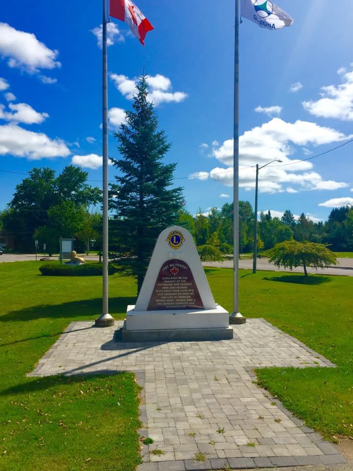 A monument in a park with flags flying in the background