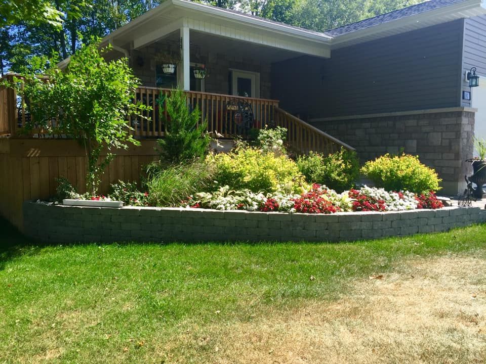 A house with a large lawn and a brick wall in front of it.