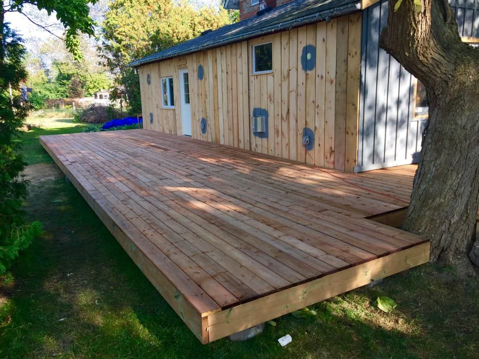 A large wooden deck is sitting in front of a house.
