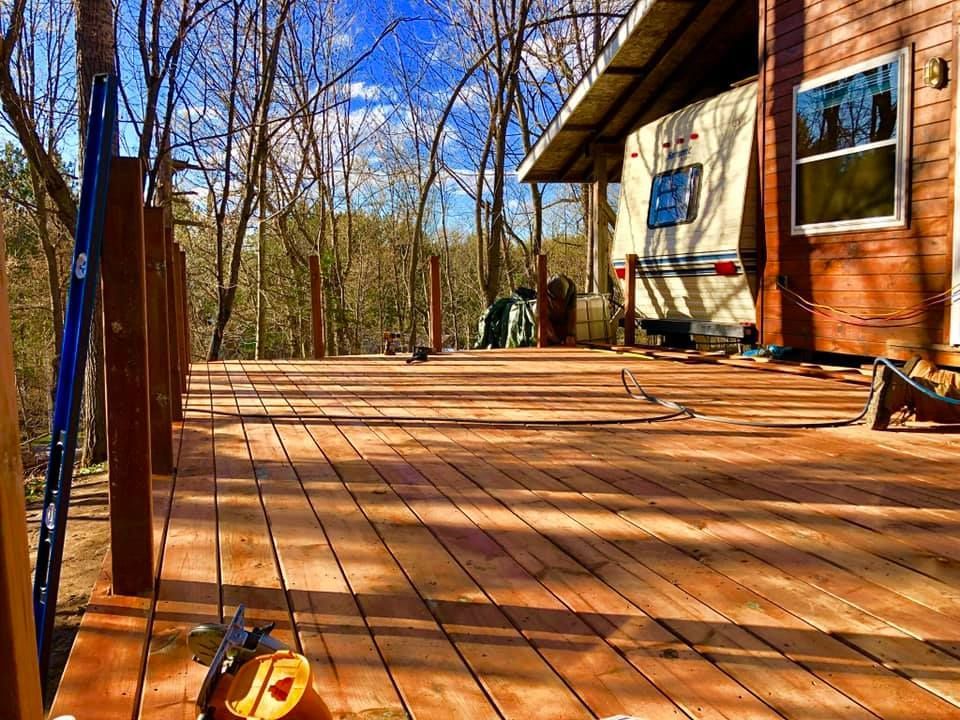 A wooden deck with a rv parked in the background.