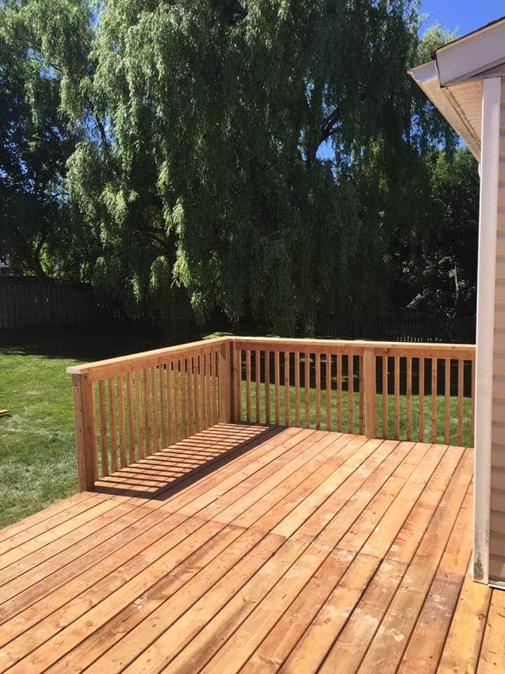 A wooden deck with a railing and trees in the background.