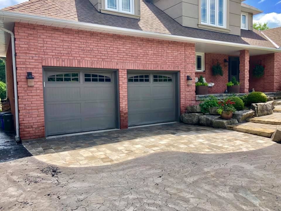 A brick house with two garage doors and a driveway.