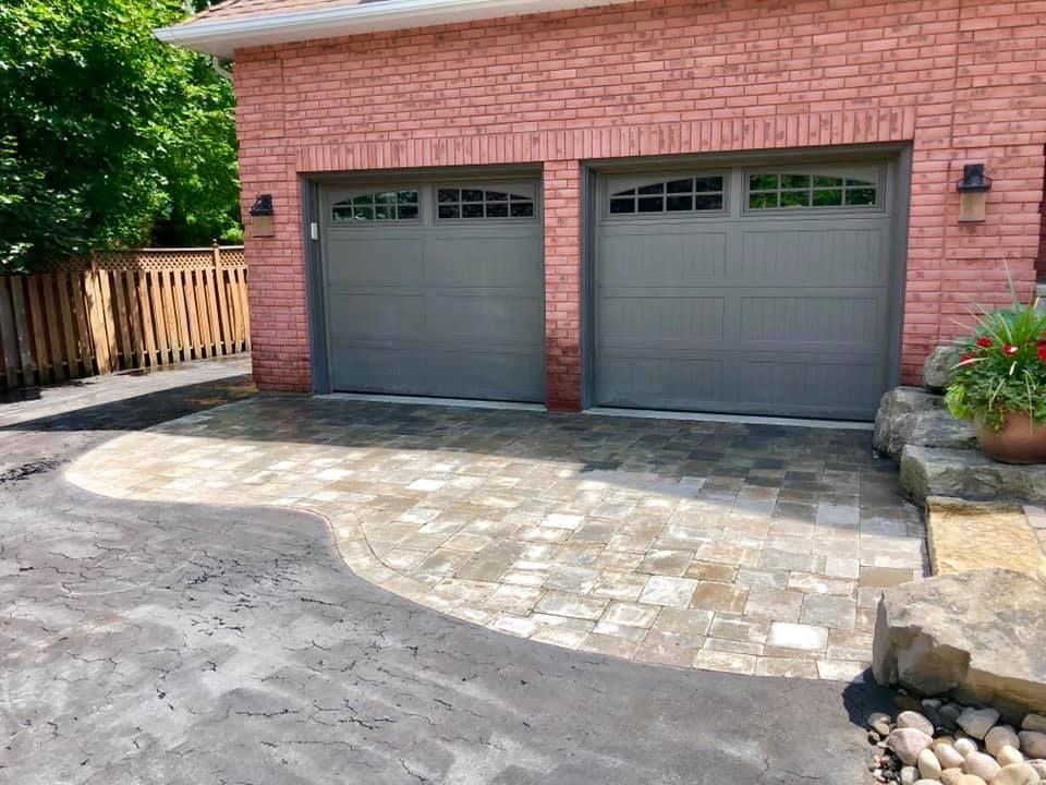 A brick house with two garage doors and a driveway.