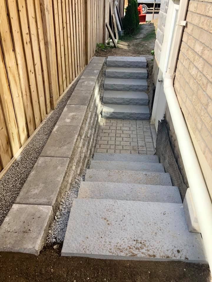 A set of stairs leading up to a basement next to a wooden fence.