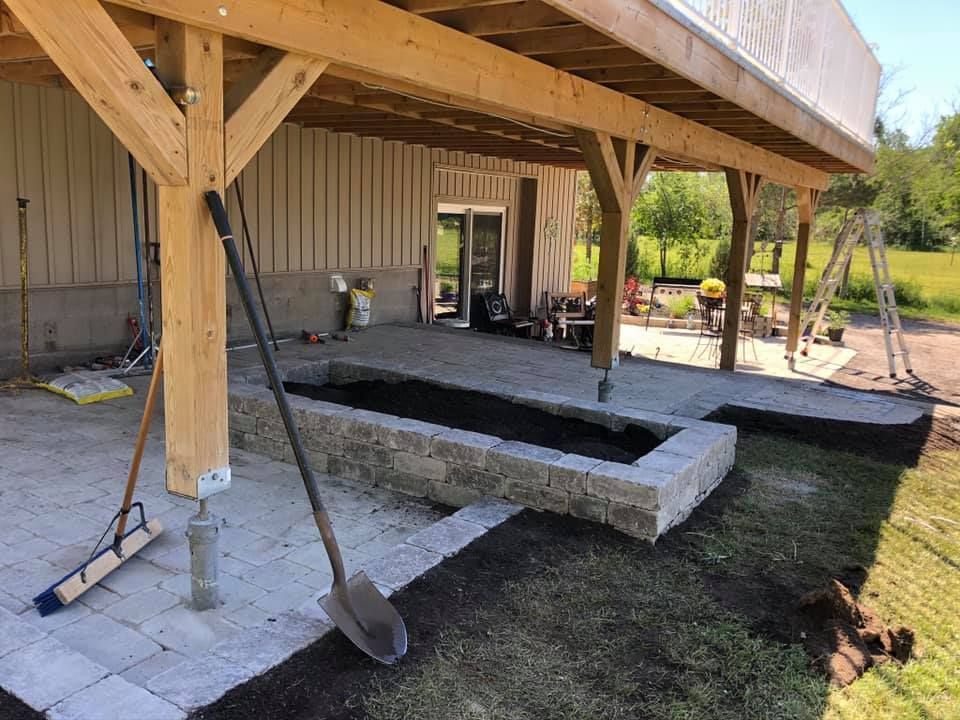 A shovel is sitting on the ground in front of a wooden structure.