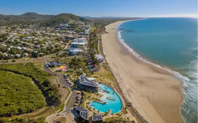 Aerial View of A Coastal Town, Beach, and Turquoise Water Under a Blue Sky — Keppel Coaches in Barmaryee, QLD