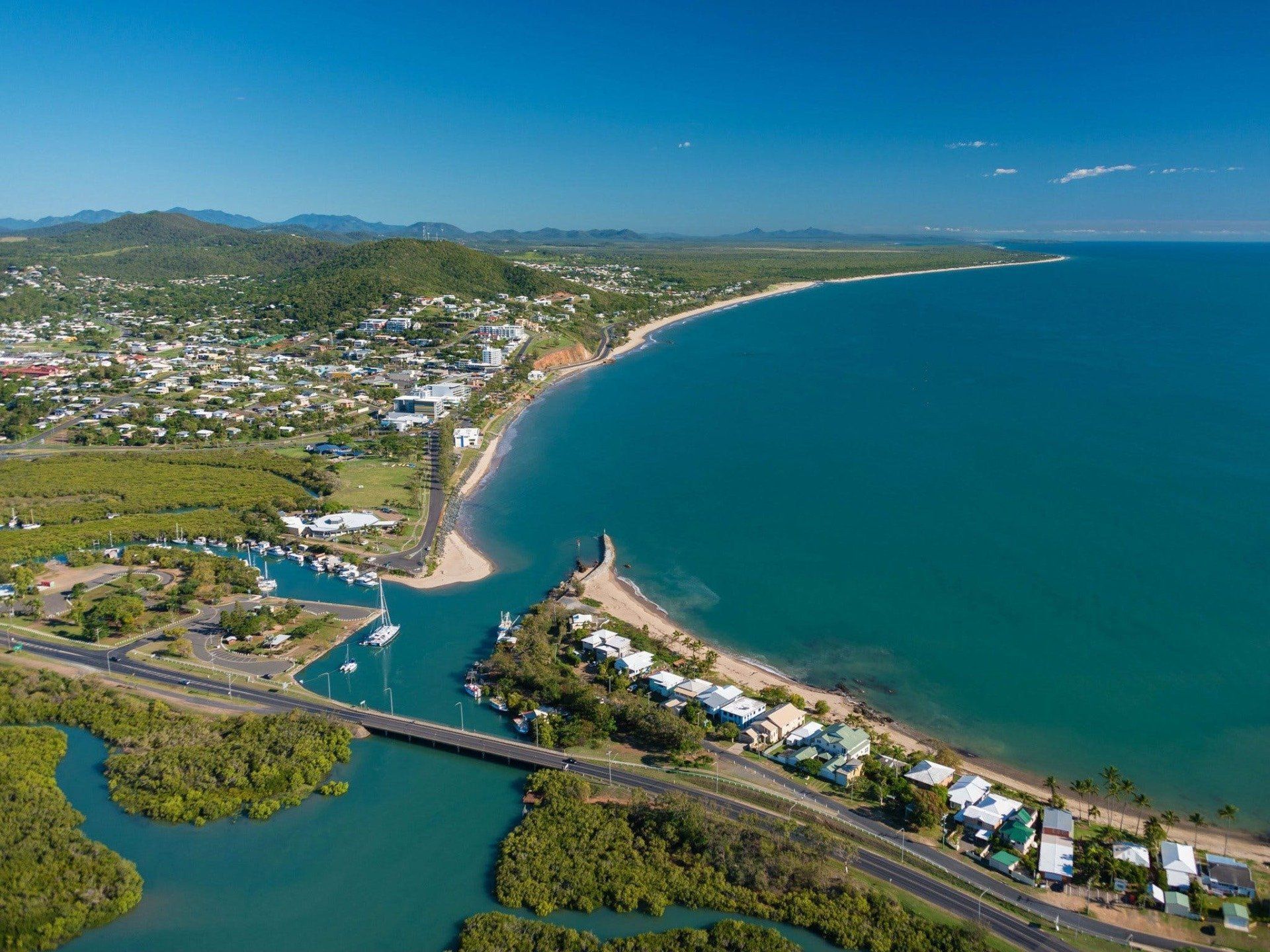 Aerial View of a Coastal Town With a Sandy Beach, Calm Turquoise Water — Keppel Coaches in Barmaryee, QLD