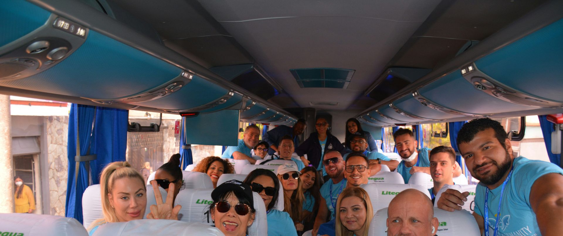 People on a bus, smiling, many wearing matching light blue shirts. Interior shot — Keppel Coaches in Barmaryee, QLD