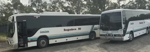 Two White Buses Parked Side by Side in Front of Trees — Keppel Coaches in Barmaryee, QLD