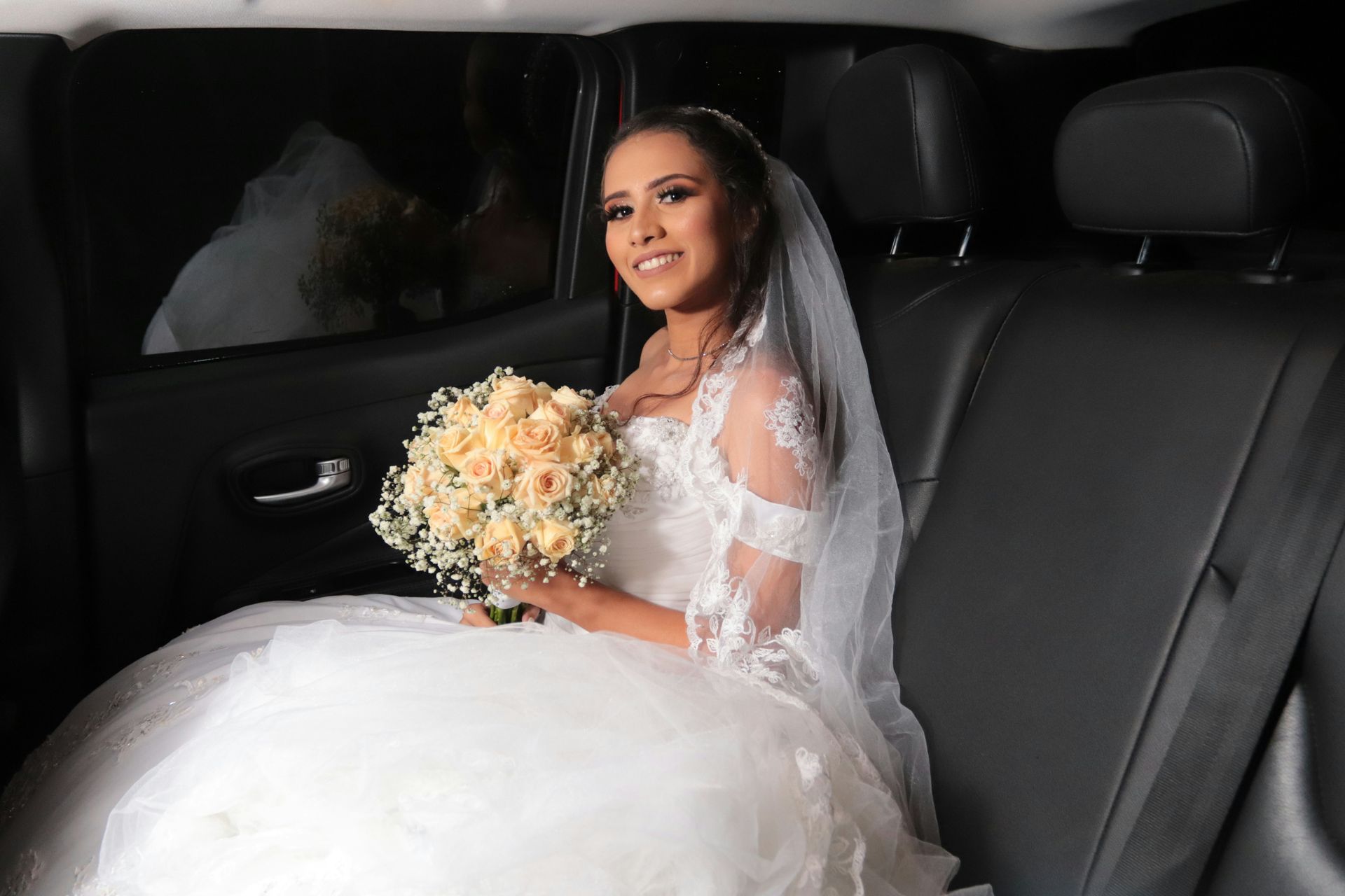 Bride in a white wedding dress and veil, holding flowers, sitting in the backseat of a car — Keppel Coaches in Barmaryee, QLD
