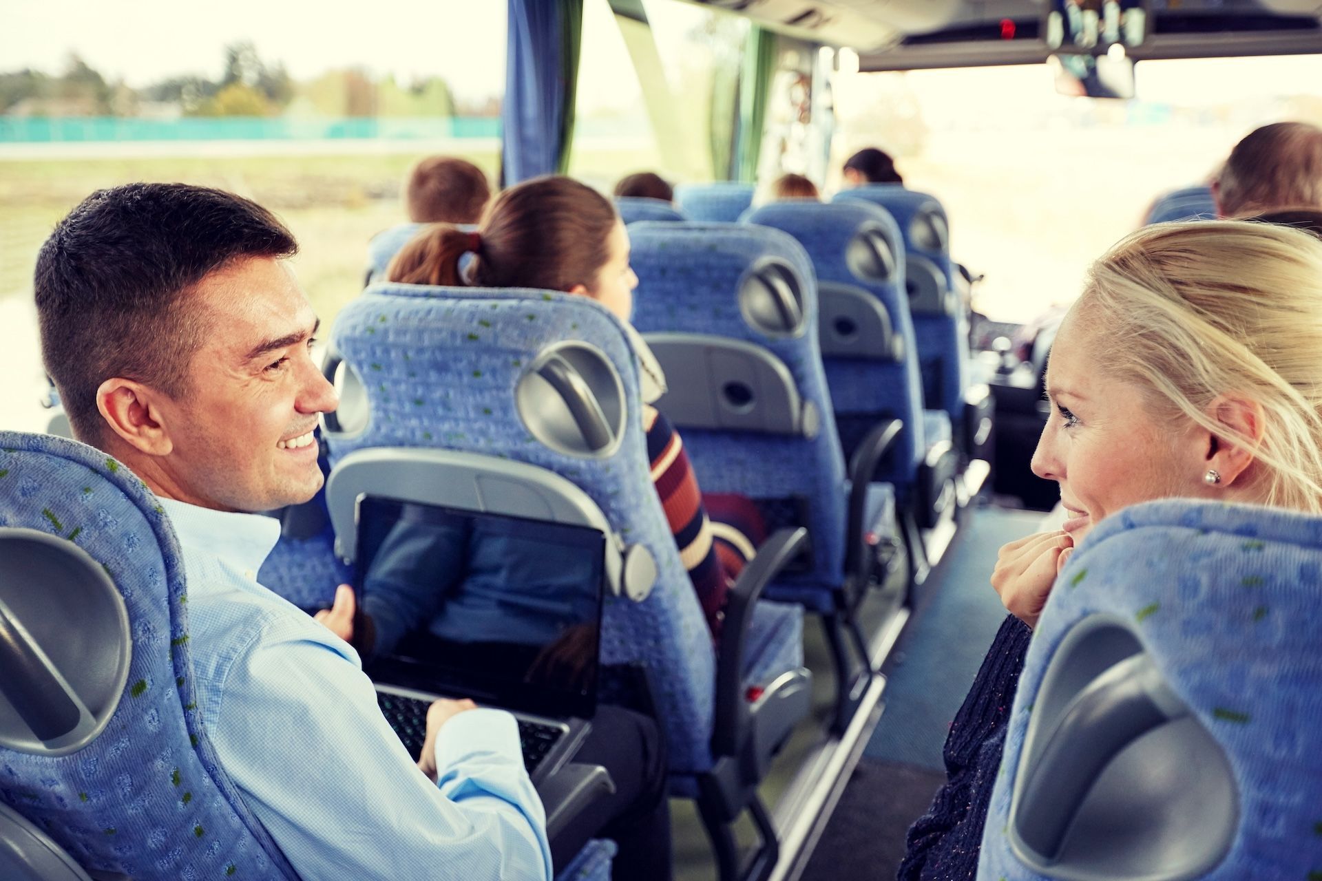 People Conversing on a Bus, Blue Seats, Man Holding Laptop — Keppel Coaches in Barmaryee, QLD
