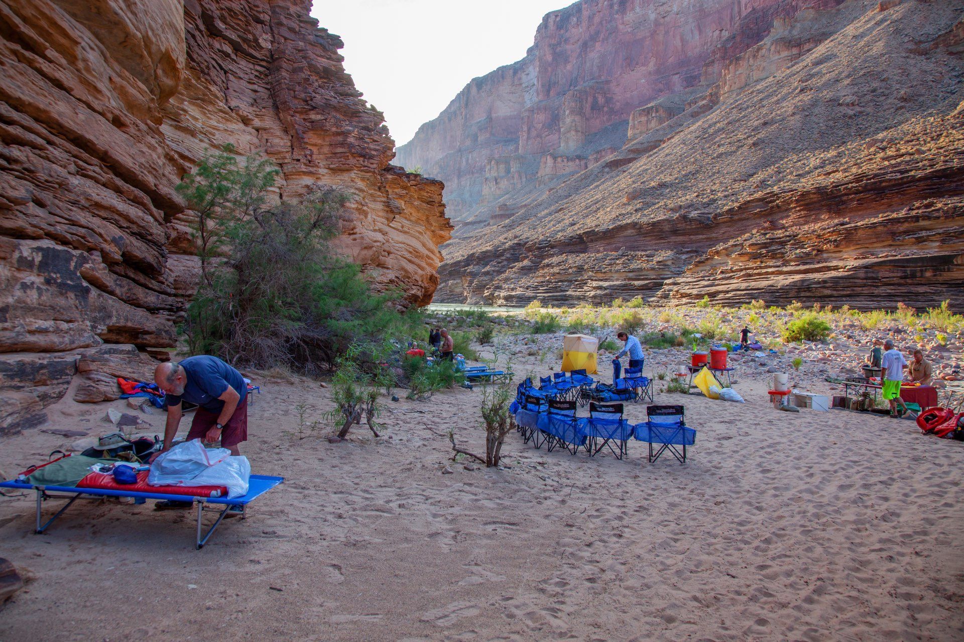 People camping in a sandy canyon with folding chairs and gear