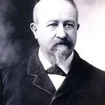 Man with a goatee in a suit and bow tie, posed for a portrait.