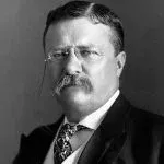 Portrait of Theodore Roosevelt in a suit, mustache, glasses, and tie.