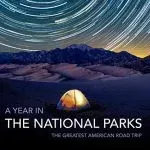 A lit tent under starry night sky, with mountains and dunes, for a National Parks road trip.