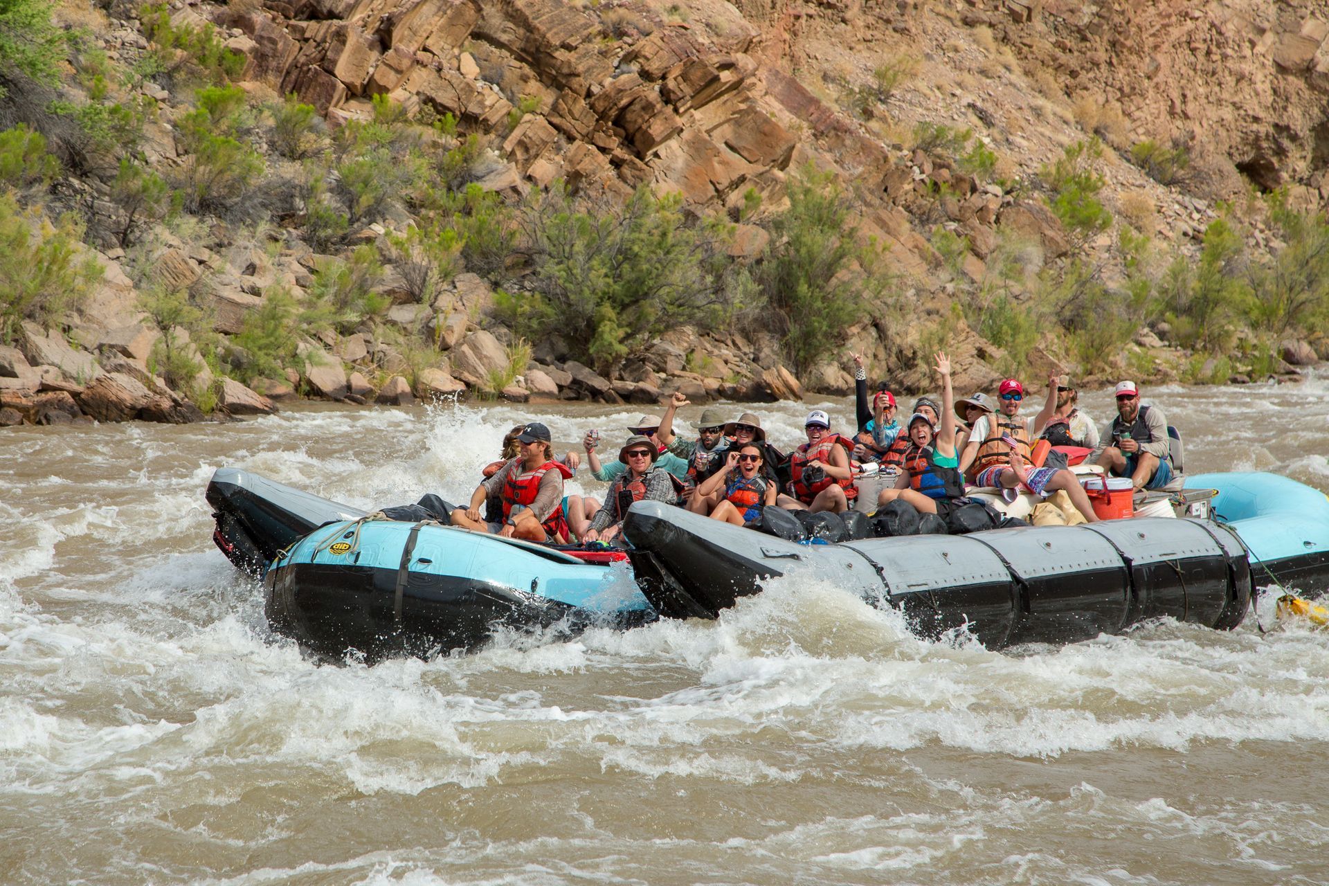 Rafting on a river with a group of people, splashing water, rocky background, sunny.